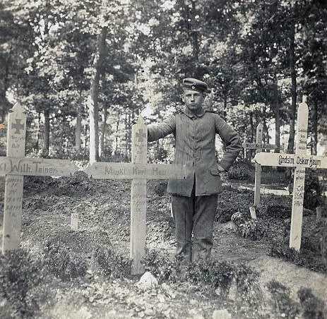 Young German soldier standing at the grave of his comrade